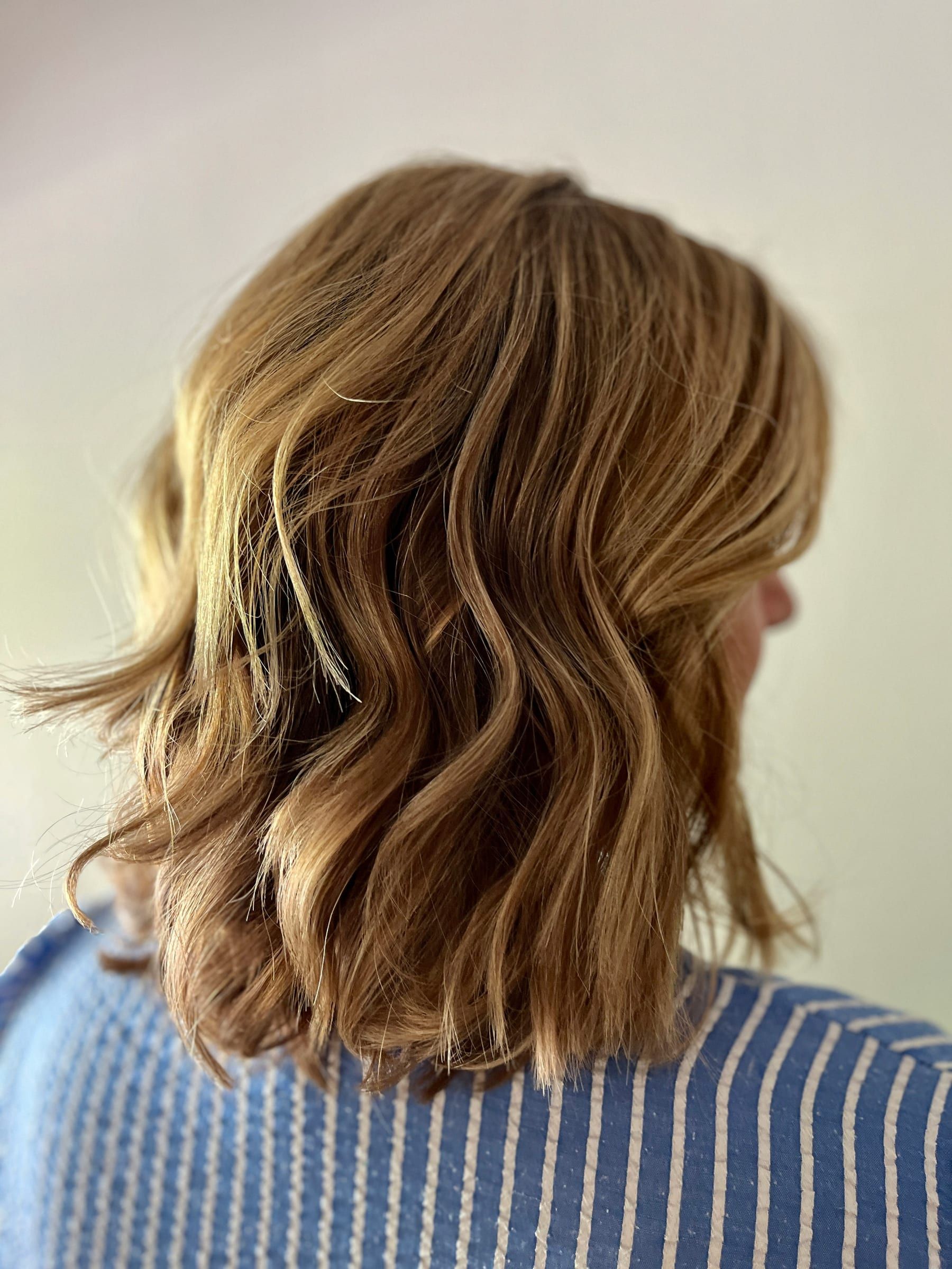 Shoulder-length honey blonde bob styled in loose, textured waves